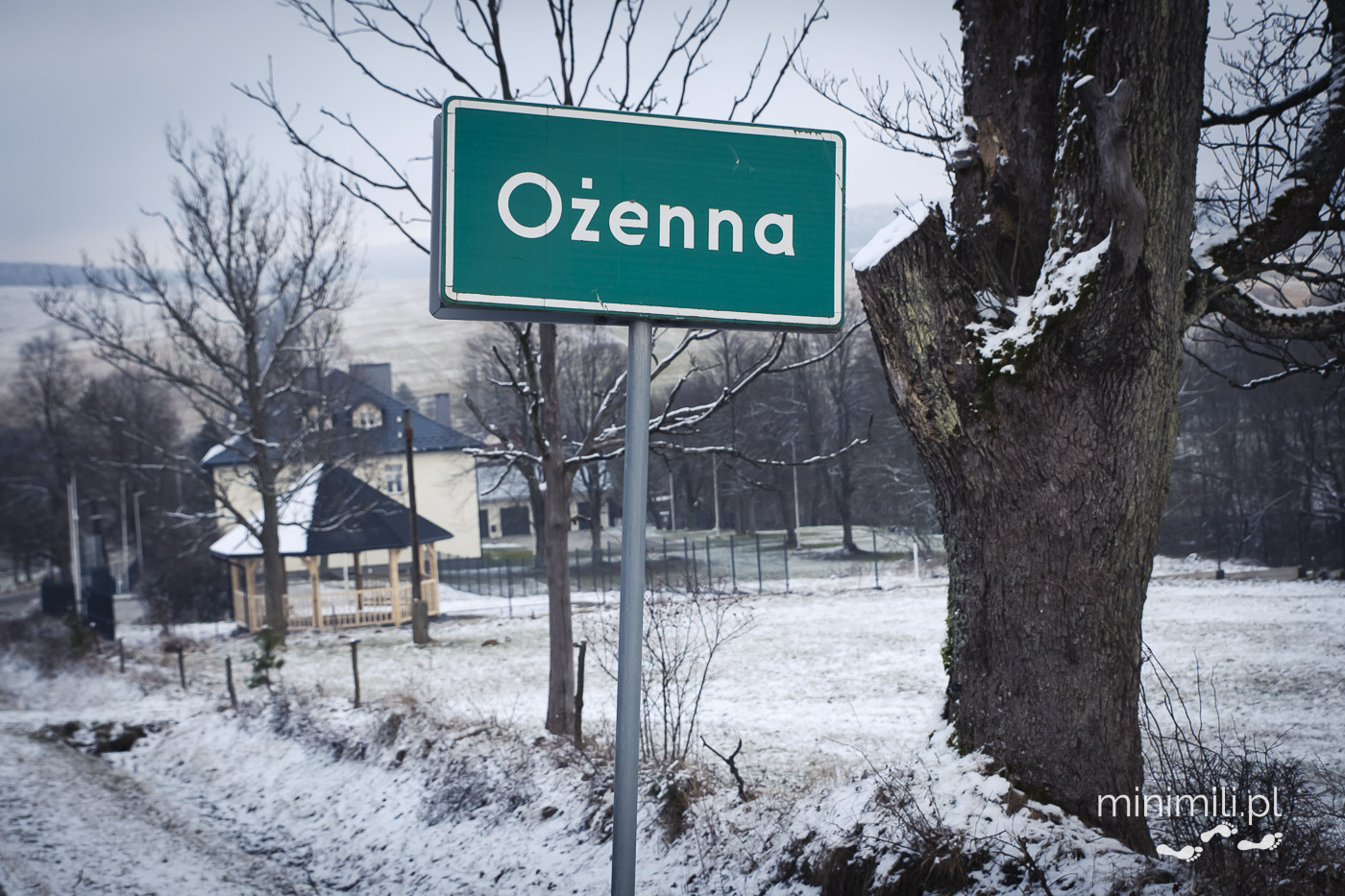 Tablica z nazwą miejscowości Ożenna w zimowej scenerii