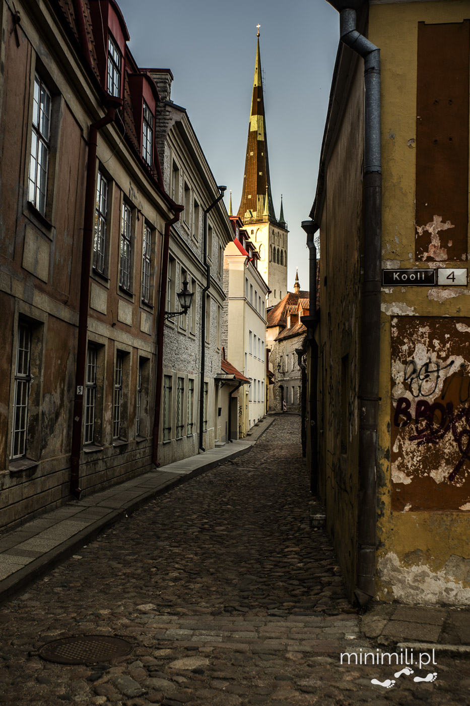 Wąska uliczka Starego Miasta w Tallinnie z widokiem na iglicę kościoła św. Olafa.
