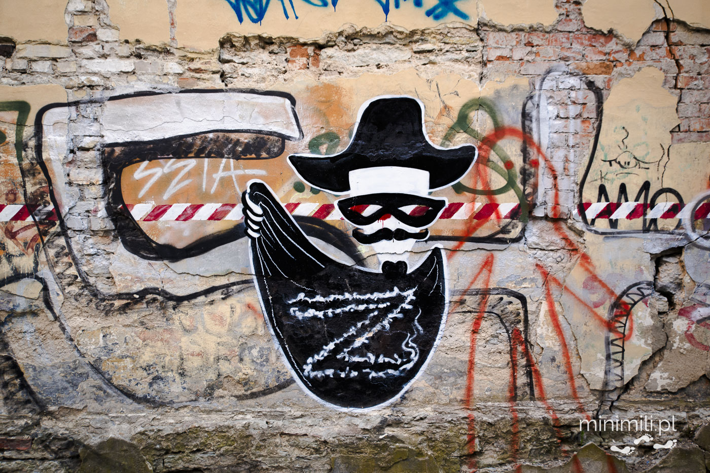 Street art w Tallinnie przedstawiający tajemniczą postać w kapeluszu.