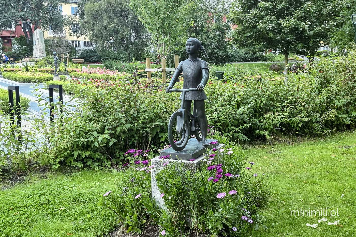 Figura dziewczynki w parku miejskim otoczona roślinnością