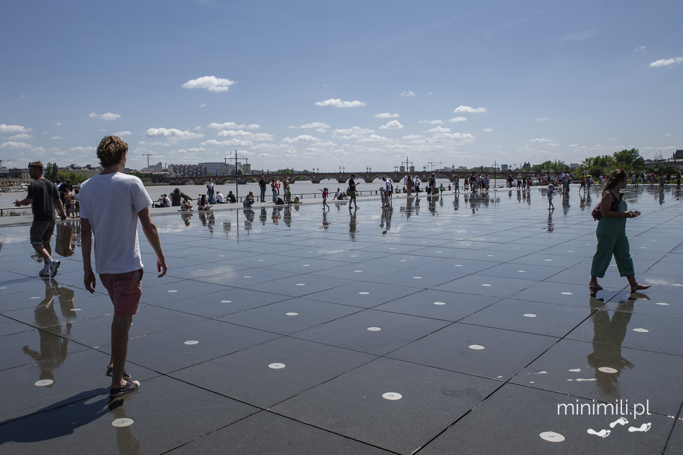 Turyści spacerujący po odbijającej niebo tafli Miroir d’Eau w Bordeaux