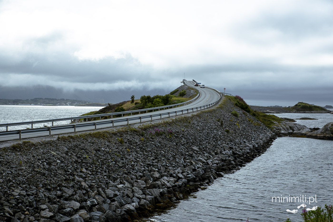 Trasa Atlantycka w Norwegii – kręta droga prowadząca przez mosty ponad kamienistym nasypem i wodą